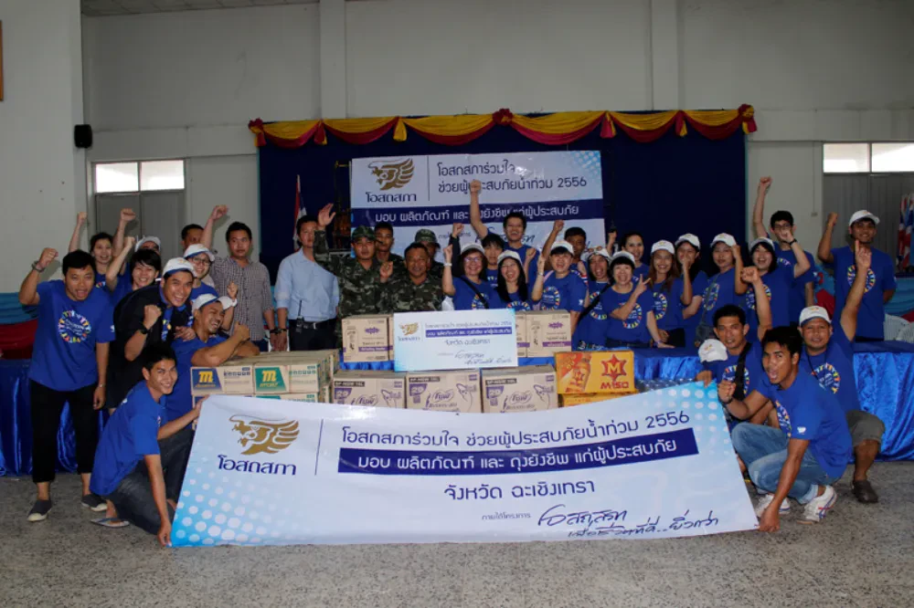 English “โอสถสภาร่วมใจ ช่วยผู้ประสบภัยน้ำท่วม” นำพนักงานจิตอาสาลงพื้นที่ มอบถุงยังชีพให้ชาวบ้าน 2,100 ชุด